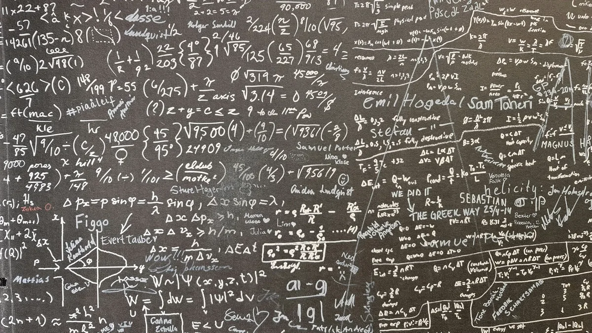 A chalkboard covered in mathematical equations and formulas, likely used for educational or research purposes.